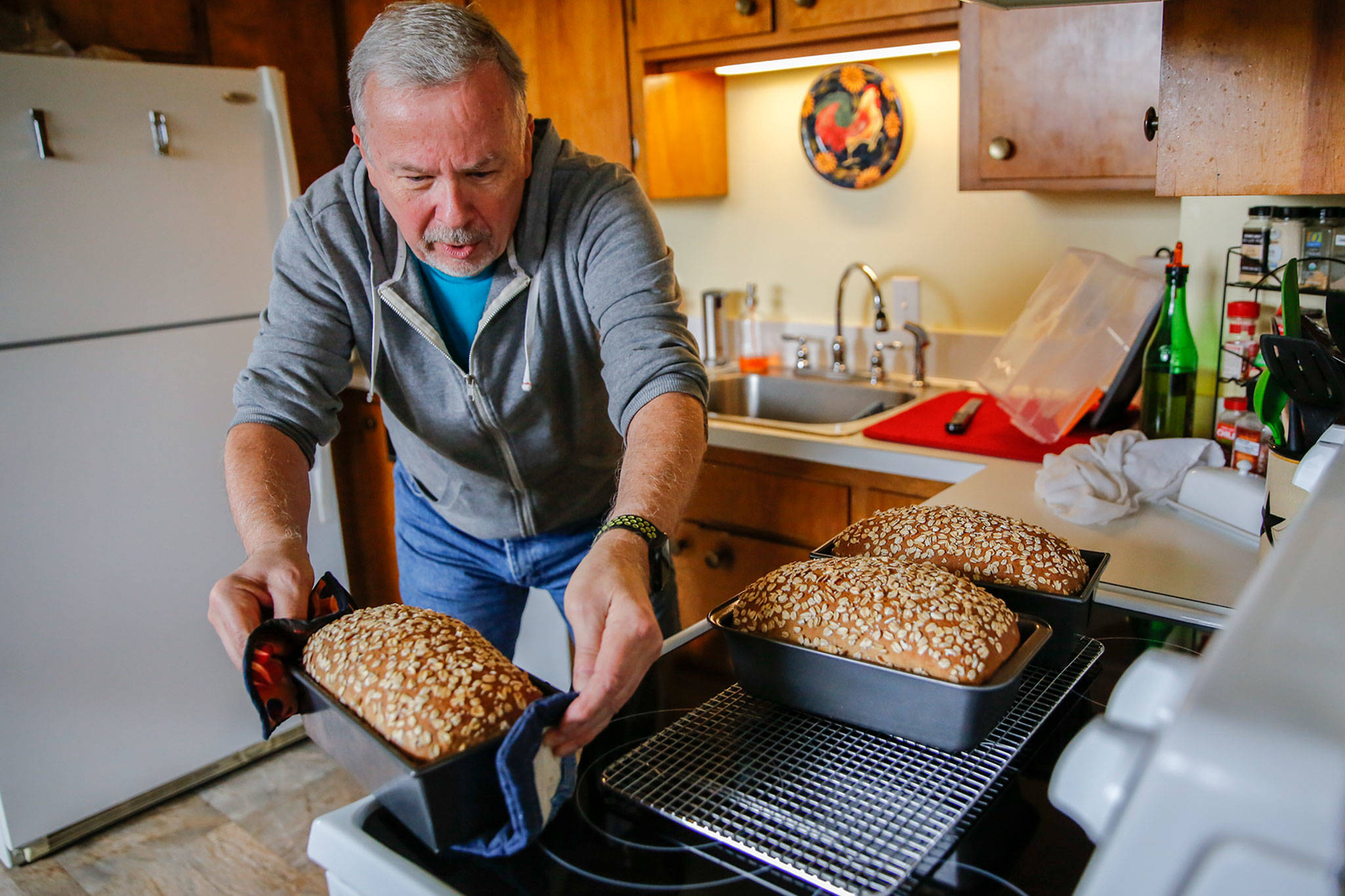 Gerry Betz, a man in a grey hoodie, sets finished loaves of bread on his counter